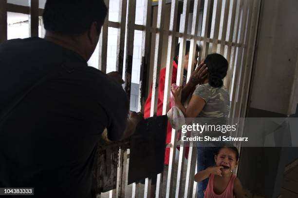 Prisoner kisses his wife goodbye as their young girl cries before masked security police transfer the new inmate in to his cell in the prison of...