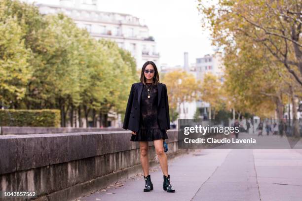 Aimee Song, wearing a black lace mini dress, black blazer, black printed boots, and blue mini bag, is seen before the Valentino show on September 30,...