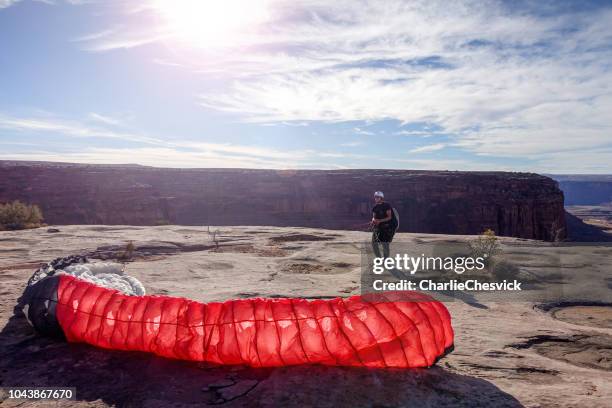 junge mähne wartet auf guten wind mit gleitschirm in wüste - hang parachute stock-fotos und bilder