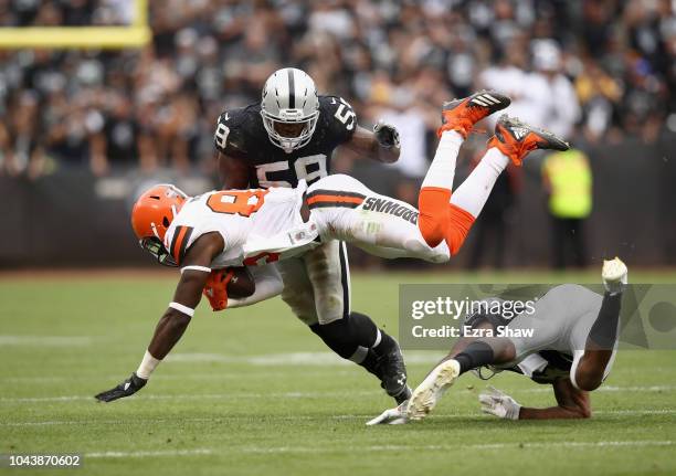 David Njoku of the Cleveland Browns is tripped up by Dominique Rodgers-Cromartie and Tahir Whitehead of the Oakland Raiders at Oakland-Alameda County...