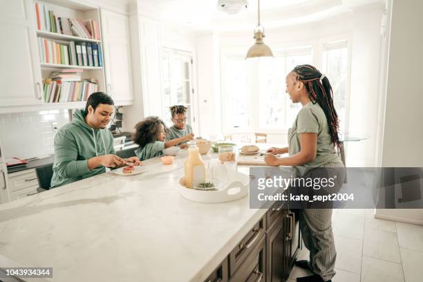 a loving mother serving her family. - kitchen island stock pictures, royalty-free photos & images