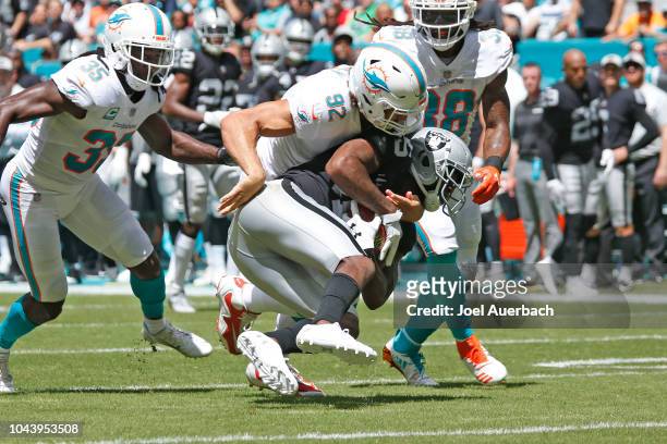 Dominique Rodgers-Cromartie of the Oakland Raiders is tackled by John Denney of the Miami Dolphins as he runs with the ball during an NFL game on...