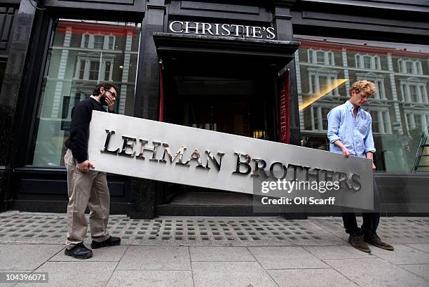 Two employees of Christie's auction house manoeuvre the Lehman Brothers corporate logo, which is estimated to sell for 3000 GBP and is featured in...