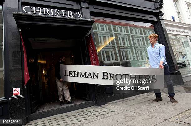 Two employees of Christie's auction house manoeuvre the Lehman Brothers corporate logo, which is estimated to sell for 3000 GBP and is featured in...