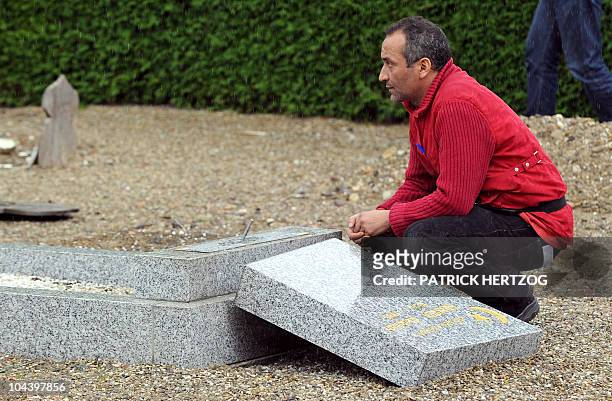 Man looks at a damaged gravestone in a cemetery where the Muslim section was desecrated by unknown vandals during the night, in the French eastern...