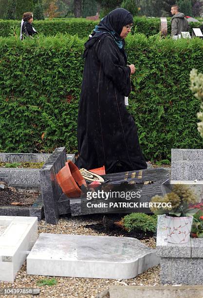Veiled woman walks past a damaged gravestone in a cemetery where the Muslim section was desecrated by unknown vandals during the night, in the French...