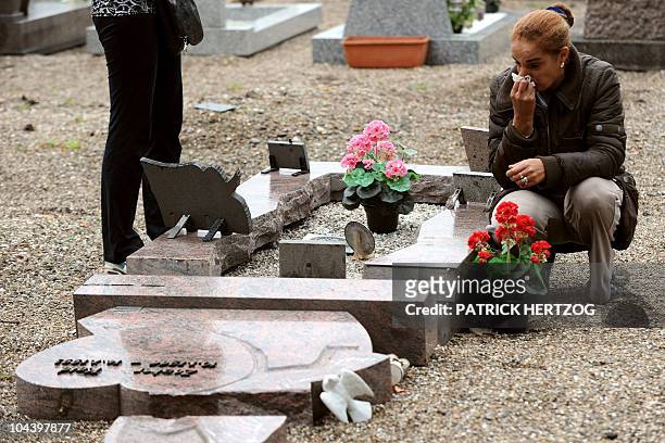 Woman looks at a damaged gravestone in a cemetery where the Muslim section was desecrated by unknown vandals during the night, in the French eastern...