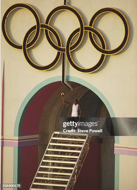 Rafer Johnson of the United States and winner of the decathlon at the 1960 Summer Olympics holds the torch aloft to light the Olympic flame during...