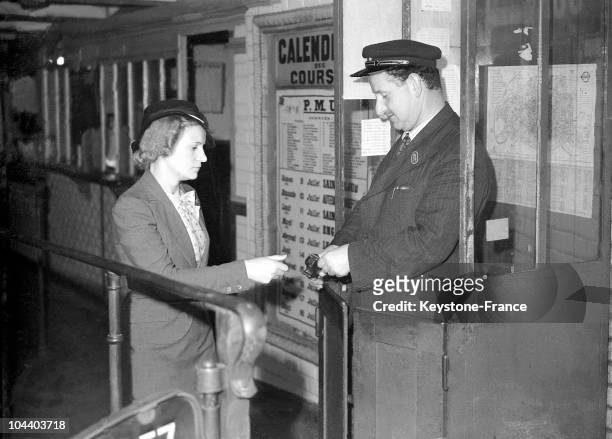 Paris. A ticket puncher punching the ticket of a woman. A person had to punch ticket at the subway's entrances before the invention of the turnstile.