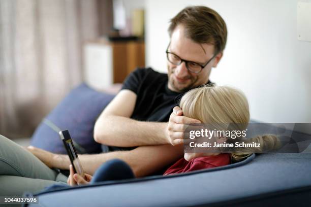 Father is covering the eyes of his child which is watching a movie on a tablet on August 14, 2018 in Berlin, Germany.