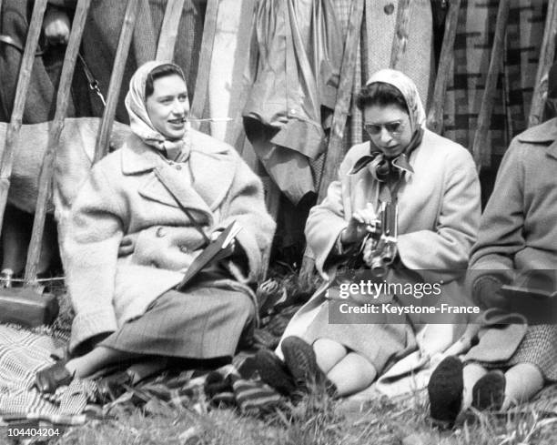 Princess MARGARET smoking a cigarette while her sister Queen ELIZABETH II is adjusting her camera. They were attending Badmington horse competition...