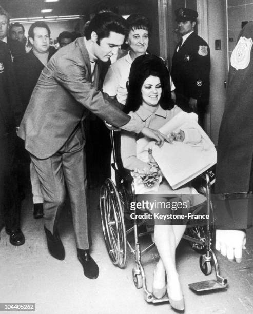 The American singer/actor Elvis PRESLEY walking beside his wife Priscilla, pictured carrying their newborn daughter Lisa Marie, on February 10, 1968.