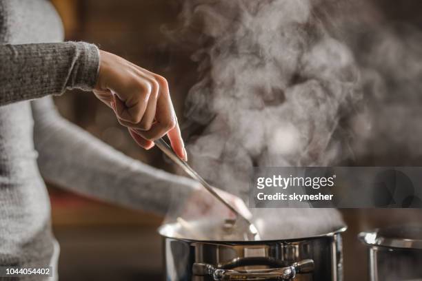 unrecognizable woman making lunch in the kitchen and stirring soup. - pot imagens e fotografias de stock