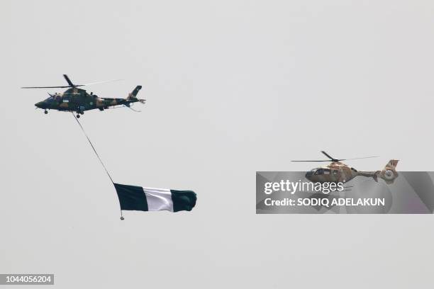 Nigerian Air Force helicopters perfom with the flag of Nigeria during a parade marking the country's 58th anniversary of independence, on October 1...