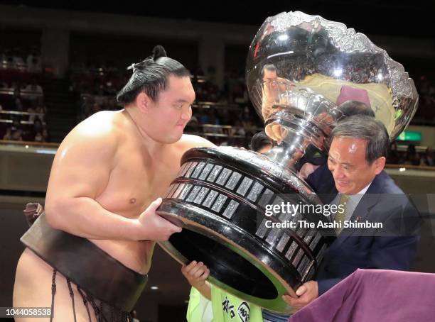Mongolian yokozuna Hakuho receives the trophy from Chief Cabinet Secretary Yoshihide Suga after winning the tournament on day fifteen of the Grand...