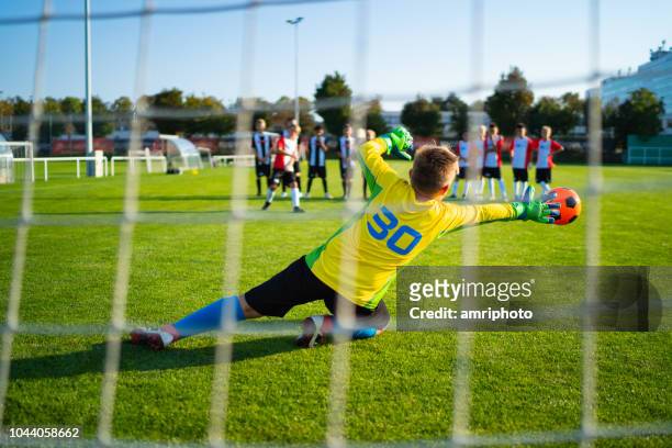junior football soccer game goalie in action - shootout stock pictures, royalty-free photos & images