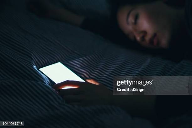 tired woman fell asleep while using smartphone in bed at night - 鳴る ストックフォトと画像