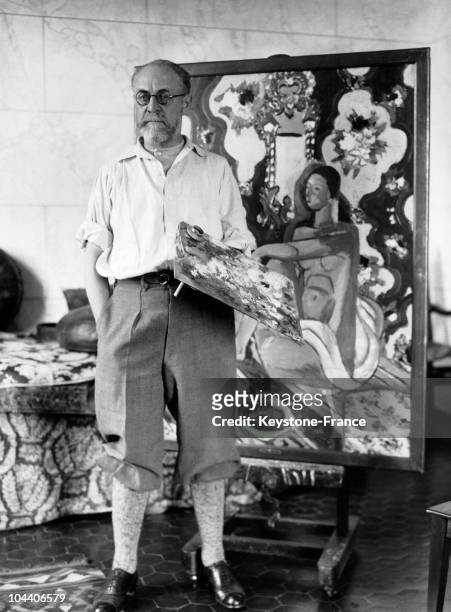 Cannes, the French painter Henri MATISSE posed in his studio. Behind him is his work FIGURE DECORATIVE SUR FOND ORNAMENTAL, painted around 1926.