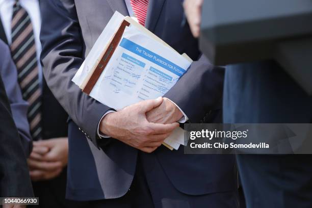 An administration official holds a document titled "The Trump Playbook for the Future" during a press conference to discuss a revised U.S. Trade...