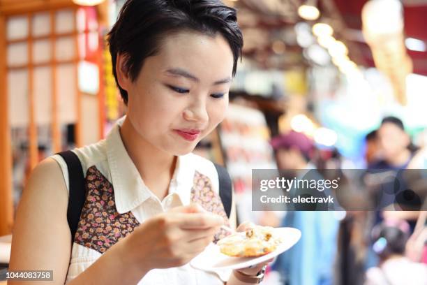 young woman eating seafood at fish market - tsukiji fish market stock pictures, royalty-free photos & images