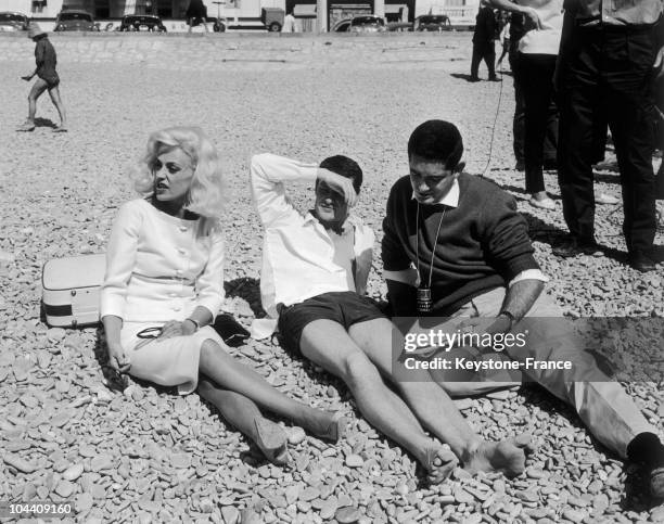 The actress Jeanne MOREAU, actor Claude MANN and director Jacques DEMY on a beach in Nice, taking a break during the filming of DEMY's film, LA BAIE...