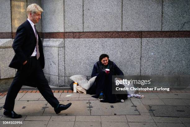 Minister for London and Minister of State for Transport Jo Johnson walks past a man begging outside the International Convention Centre during day...