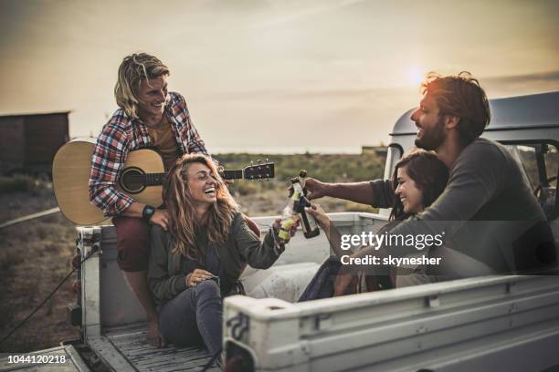 happy couples toasting in pick-up truck at sunset. - beer truck stock pictures, royalty-free photos & images