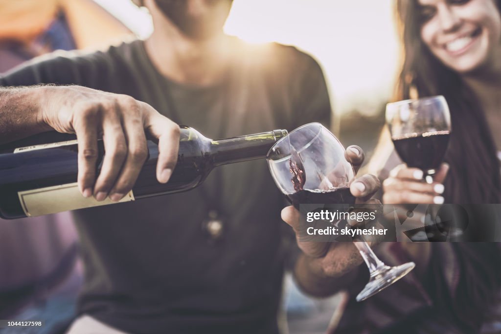 Close up of pouring red wine into a glass outdoors.