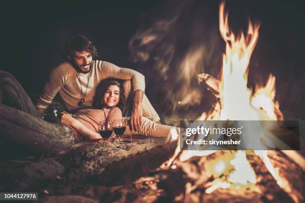 heureux couple détendue bénéficiant à leur soirée du feu de camp. - feu plage photos et images de collection