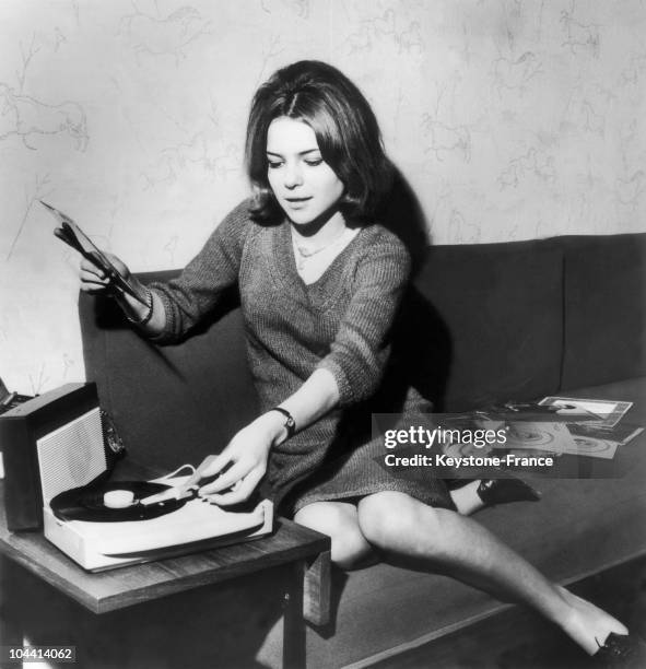 France GALL, sitting on a couch, starts up a record player, on April 9, 1964.\\France GALL assise sur un canape met en route le tourne-disque le 9...