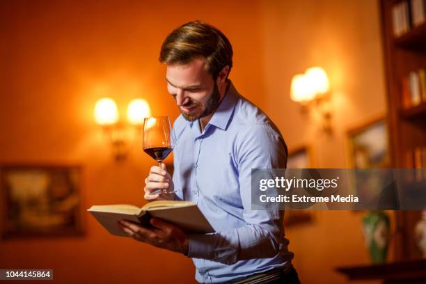 man holding a book and wineglass - wine library stock pictures, royalty-free photos & images