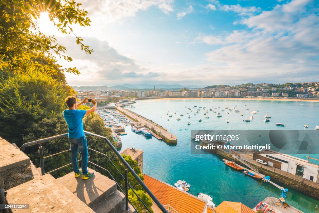 Tourist photographing La Concha bay and San Sebastian, Spain