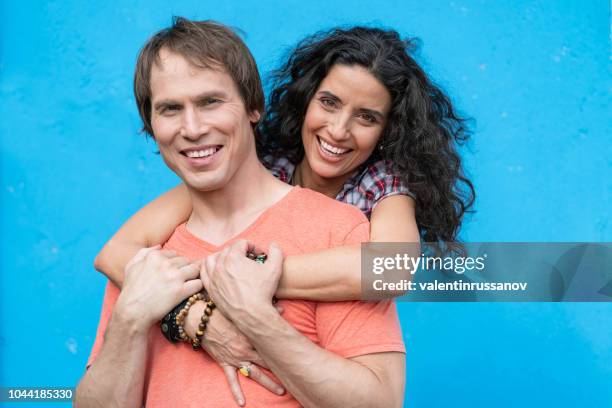 mid adult couple embracing on blue background - couple coloured background stock pictures, royalty-free photos & images