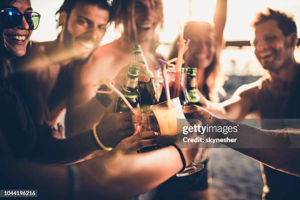 close up of happy friends toasting with alcohol at sunset. - beach cocktail stock pictures, royalty-free photos & images