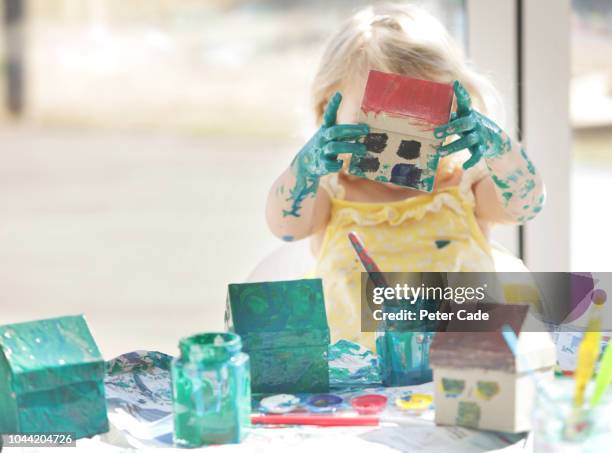 young girl painting small cardboard houses - school reform stock pictures, royalty-free photos & images