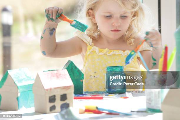 young girl painting small cardboard houses - cuarto de jugar fotografías e imágenes de stock