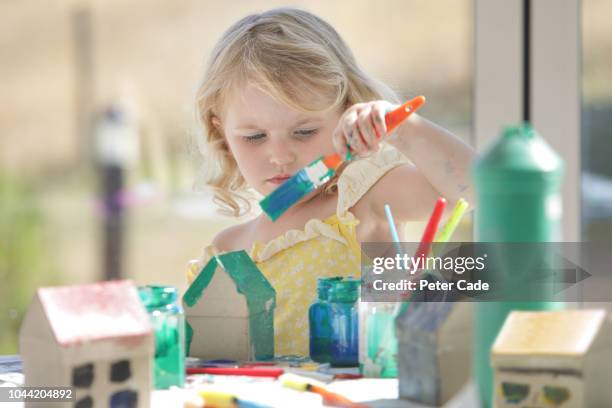 young girl painting small cardboard houses - messy playroom stock-fotos und bilder