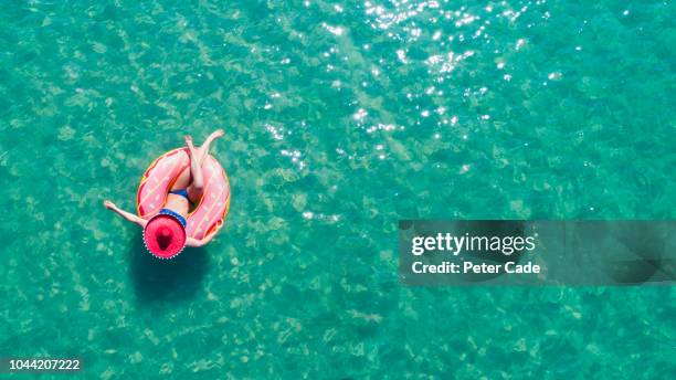 lady floating in the sea in a rubber ring, wearing large hat - inflatable ring 個照片及圖片檔