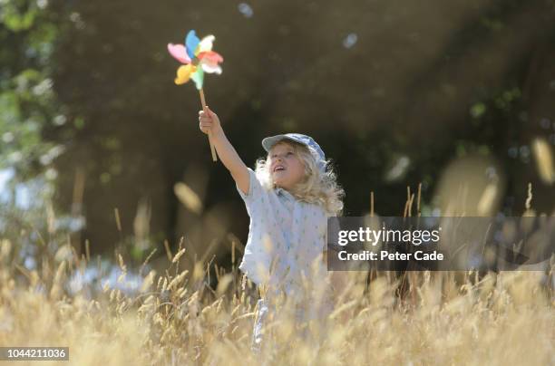 young girl playing with toy windmill in field - air child play stock-fotos und bilder