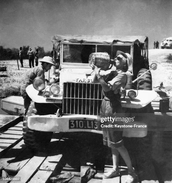 Une Participante Au Rallye Mediterranee-La Cap Se Desaltere Devant Sa Voiture Avant D'Arriver a Fort-Archambault Au Tchad Le 7 Fevrier 1951.