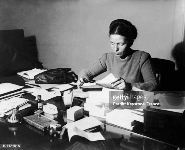 The French Writer Simone De Beauvoir Seated, Reading At Her Desk In 1953.