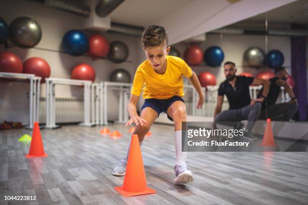 child running from a cone to cone during his warm up with a personal trainer - cone shape stock pictures, royalty-free photos & images