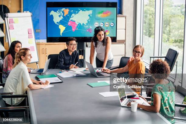 mixed ethnicity women only group discussing strategy - world map office stock pictures, royalty-free photos & images