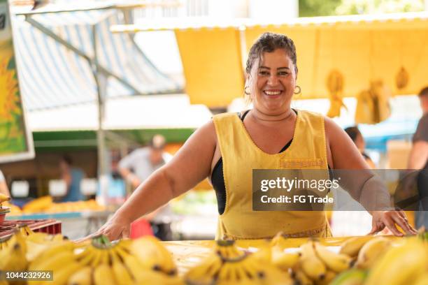 porträt von zuversichtlich besitzer - verkauf von bananen am bauernmarkt - straßenverkäufer stock-fotos und bilder