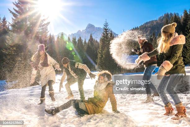 amis ayant la boule de neige se battre dans la neige par journée ensoleillée - bataille boule de neige photos et images de collection
