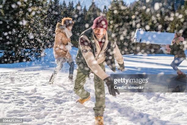 man throwing snowball into air while having fun with his friends - slovenia winter stock pictures, royalty-free photos & images