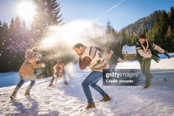 freunde, die schneeball kämpfen im schnee an sonnigen tag - schneeball effekt stock-fotos und bilder