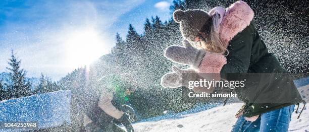 freunde, die schneeball kämpfen im schnee an sonnigen tag - schneeball effekt stock-fotos und bilder
