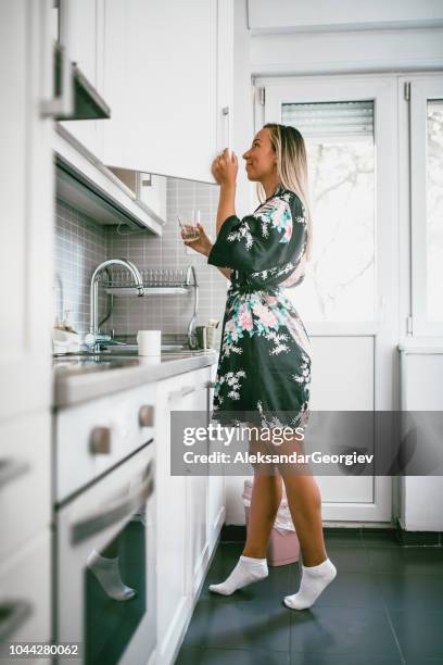 schattig meisje is op zoek naar een koffie van pantry keuken - voorraadkast stockfoto's en -beelden