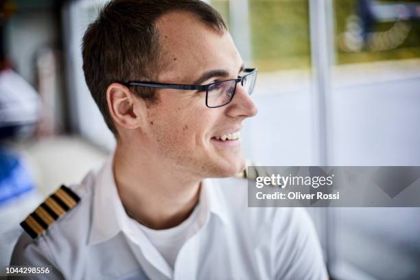 smiling young pilot in airplane hangar looking out of window - hangar stock-fotos und bilder